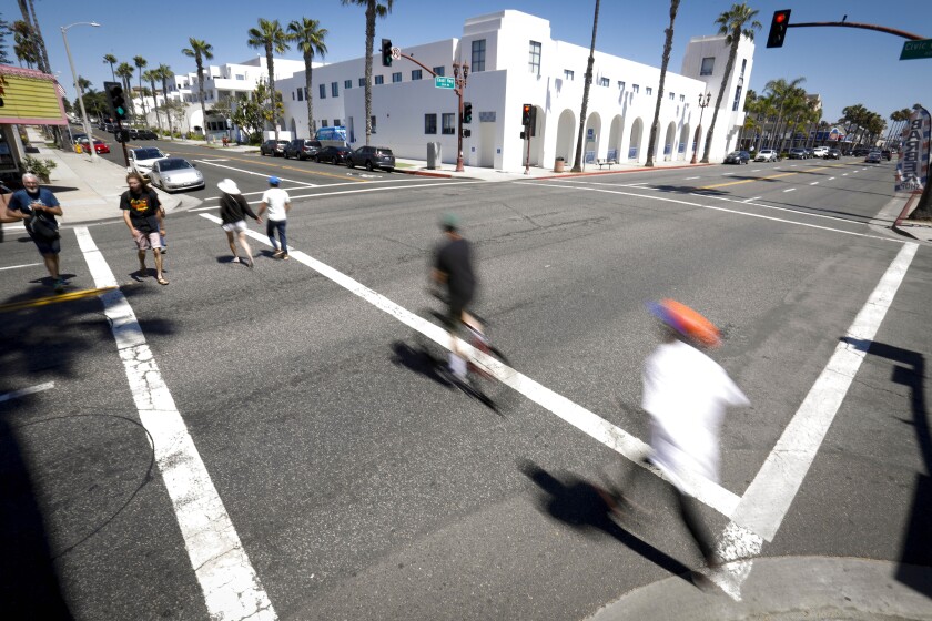 Pedestrians walk across Coast Highway on Thursday at Civic Center Drive, one of six intersections where the city plans to install roundabouts.