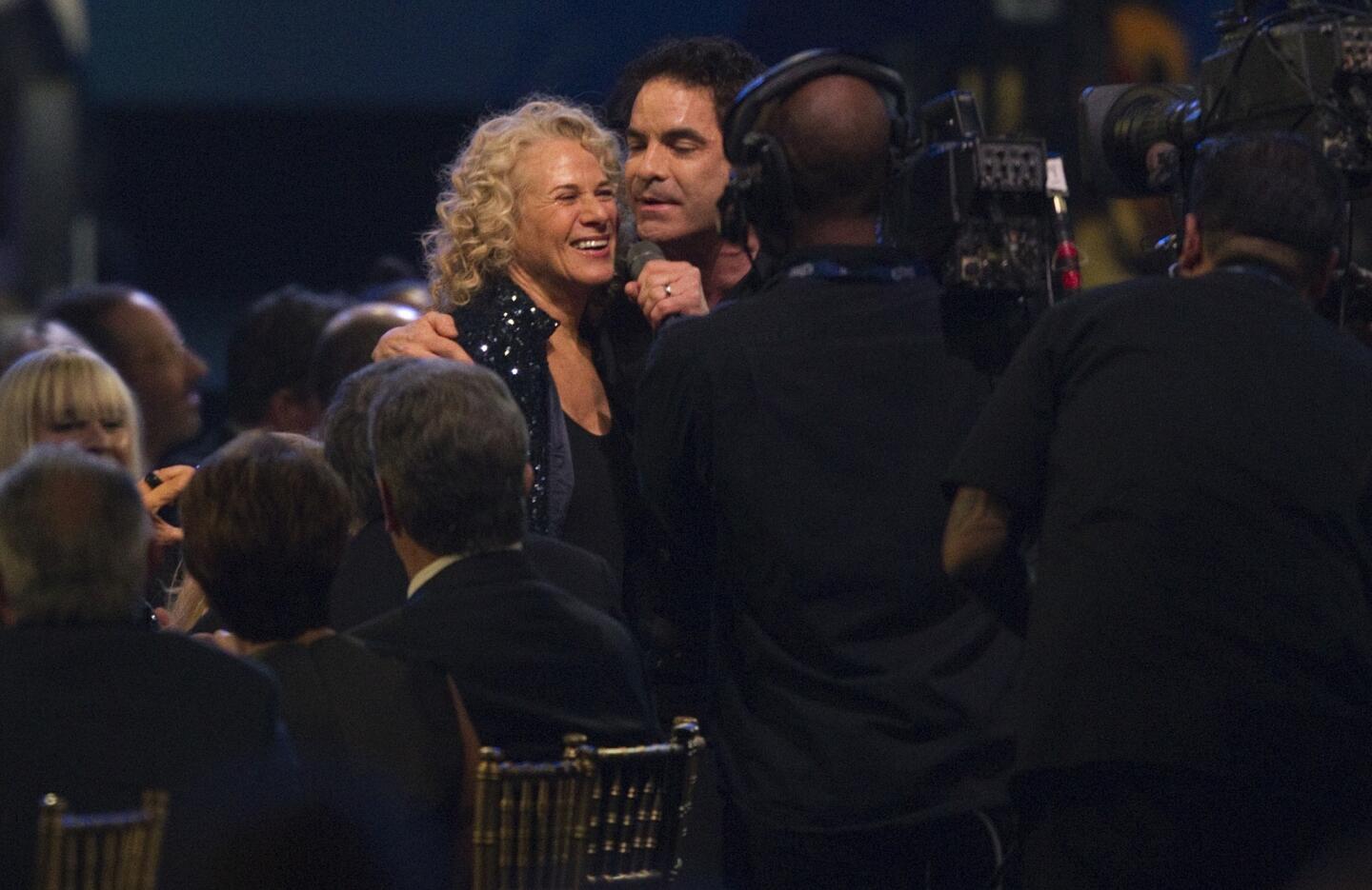 Pat Monahan grasps the shoulder of Carole King in the audience while singing one of her songs during the MusiCares Person of the Year concert honoring King.