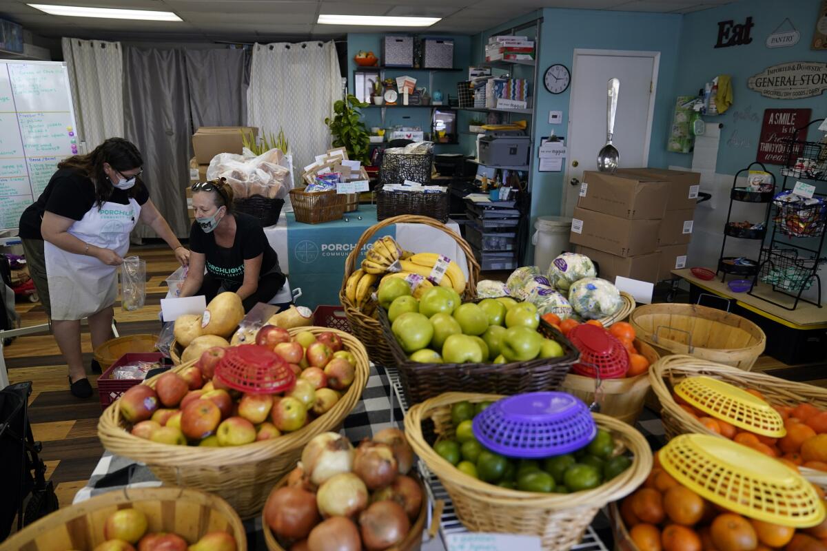 Two women at a food pantry with baskets of produce