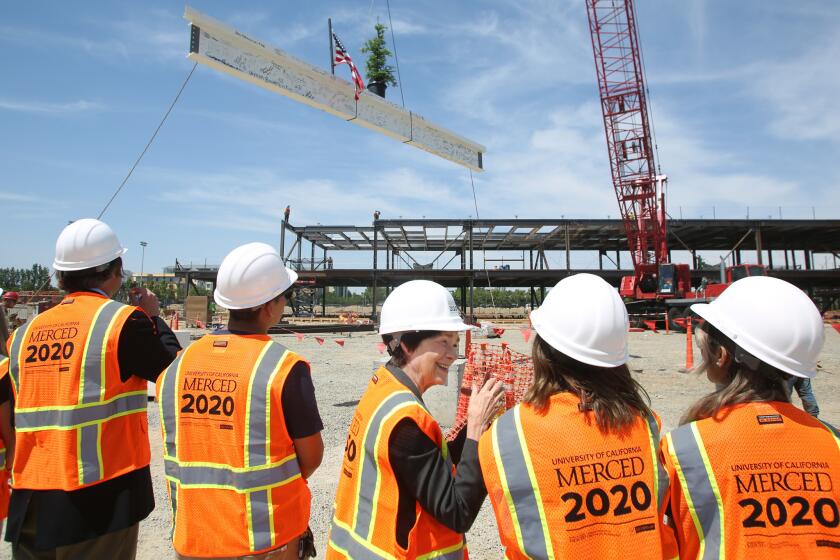UC Merced Chancellor Dorothy Leland and student leaders watch the final beam of the final building get positioned into place in Merced, Calif., Tuesday, May 7, 2019. FOR THE TIMES/GARY KAZANJIAN