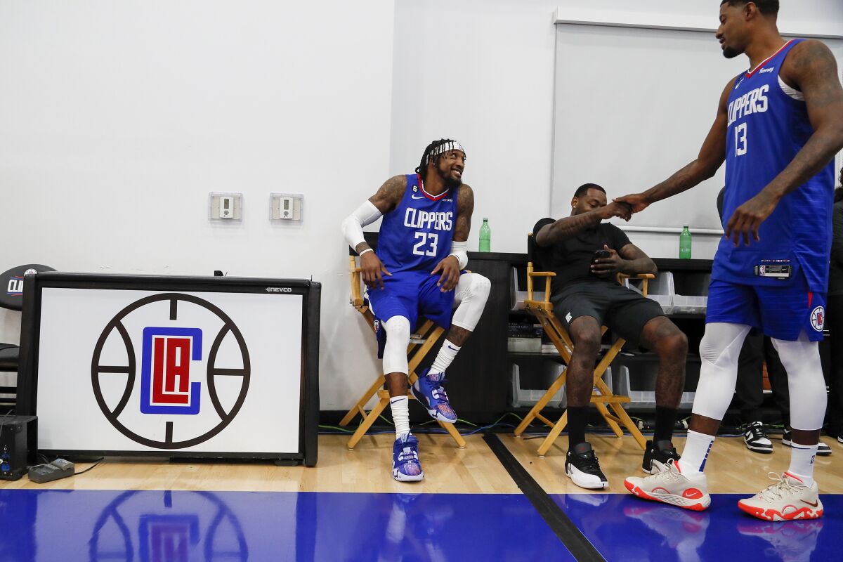 Robert Covington, left, and John Wall greet Paul George during media day.