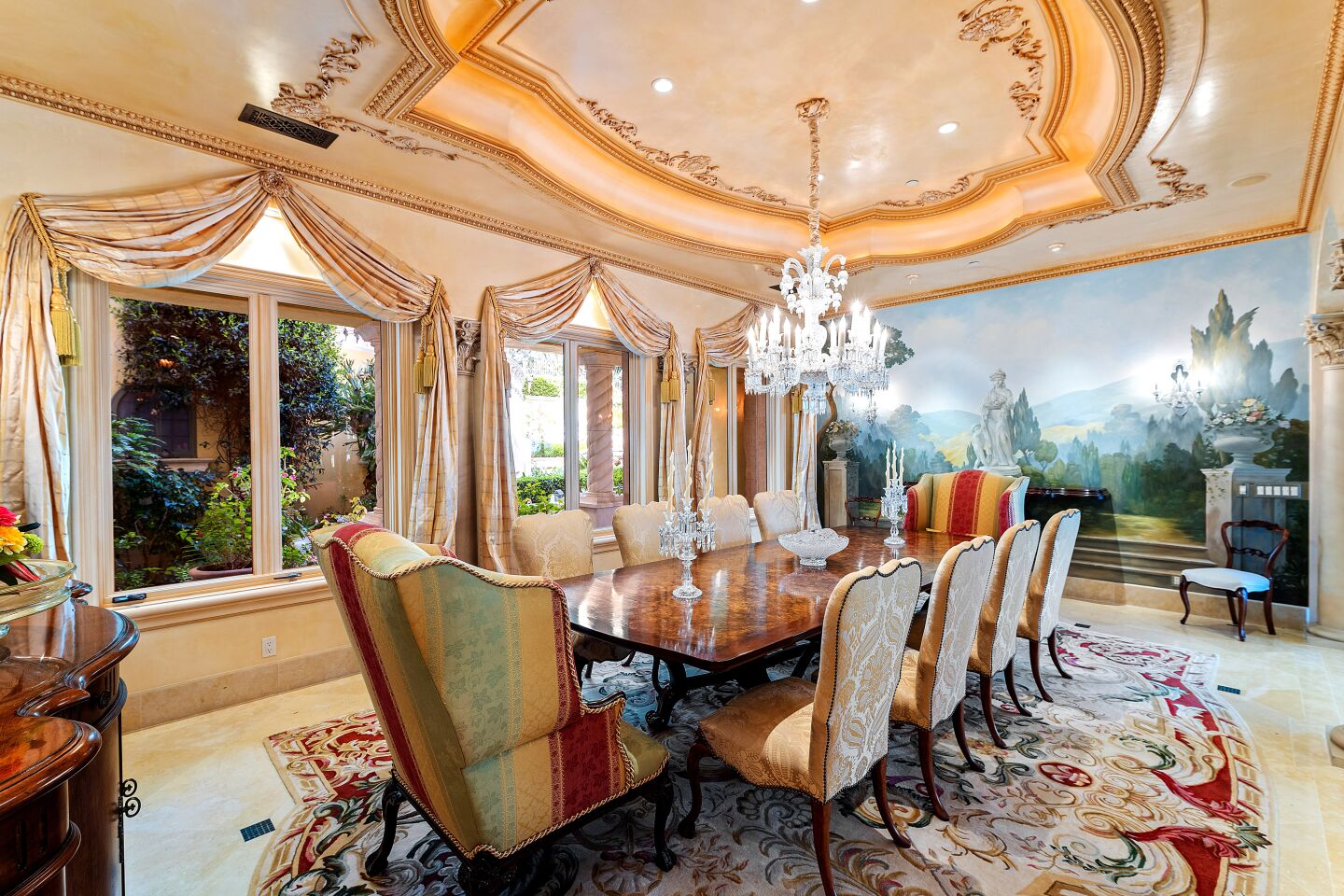 A sculpted ceiling, chandelier and mural of a bucolic scene in the dining room.