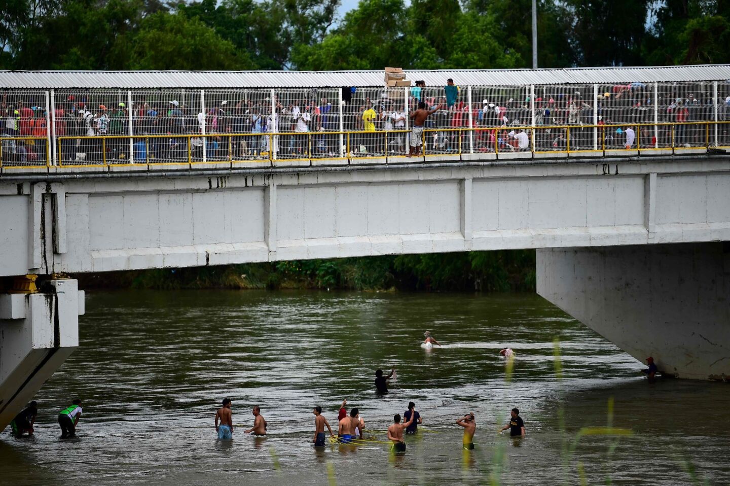Honduran migrants heading in a caravan toward the United States wait to help fellow men get down to the Suchiate River from the Guatemala-Mexico international border bridge, in Ciudad Hidalgo, Chiapas state, Mexico.