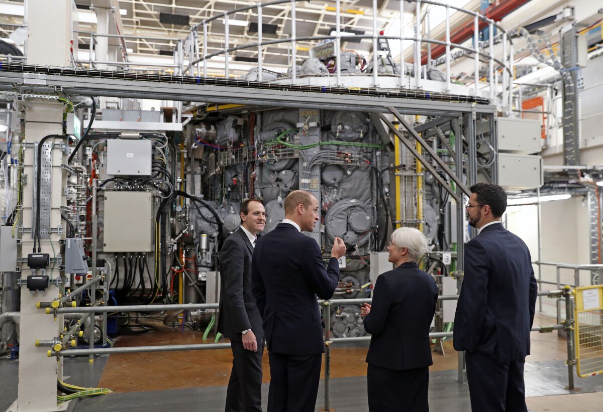 FILE - Britain's Prince William, Duke of Cambridge, 2nd left, talks with Professor Ian Chapman, CEO of the UK Atomic Energy Authority, left, Nanna Heiberg, 2nd right, and Joseph Milnes, head of engineering design unit, right, alongside the MAST Upgrade chamber, during his visit to the UK Atomic Energy Authority (UKAEA) at the Culham Science Centre in Abingdon, southern England, Thursday Oct. 18, 2018. Prince William officially marked the end of the construction of the MAST (Mega Amp Spherical Tokamak) Upgrade Fusion Experiment. Researchers at the Joint European Torus experiment near Oxford managed to produce a record amount of heat energy over a five-second period, which was the duration of the experiment, the U.K. Atomic Energy Authority announced on Wednesday, Feb. 9, 2022. (Adrian Dennis/Pool via AP, File)