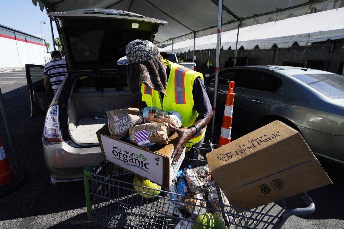 A volunteer fills up a vehicle with food boxes at the St. Mary's Food Bank Wednesday, June 29, 2022, in Phoenix. The food banks are struggling to meet the growing need even as federal programs provide less food to distribute, grocery store donations wane and cash gifts don’t go nearly as far. (AP Photo/Ross D. Franklin)