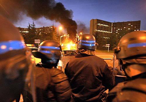 Policemen stand guard as a bus is burning at the entrance of Le Mirail, a neighborhood of Toulouse.