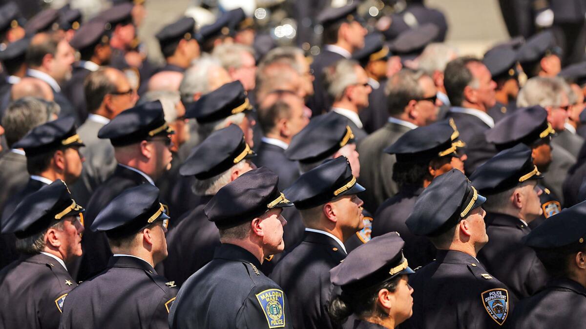 Police officers stand at attention as the casket for fallen New York City police officer Brian Moore is brought into a Long Island church