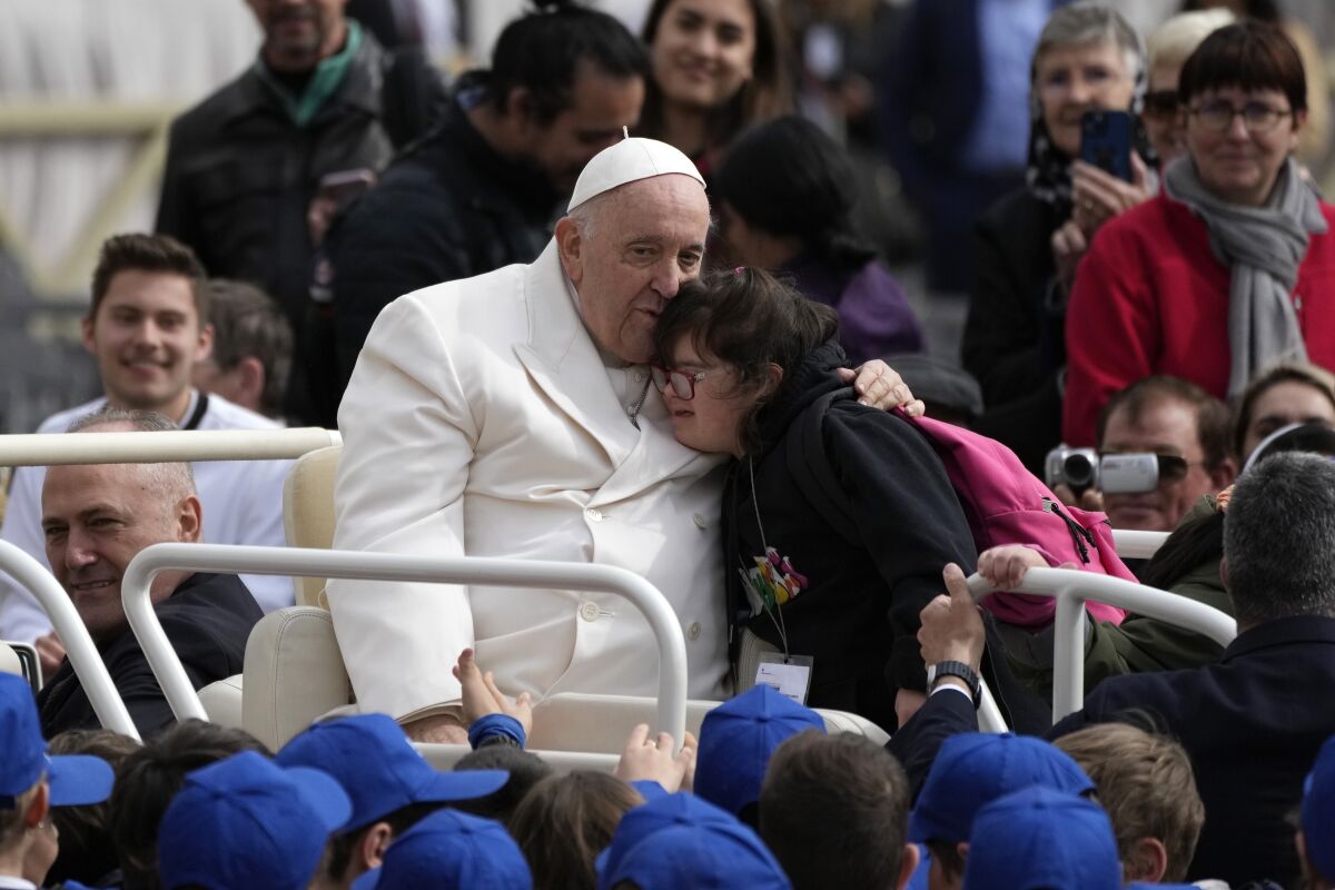 Pope Francis hugs a child at the end of his weekly general audience in St. Peter's Square.