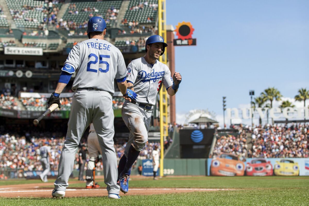 Los Angeles Dodgers Chris Taylor, right, celebrates with David Freese after scoring a run against the San Francisco Giants in the first inning of a baseball game in San Francisco, Sunday, Sept. 30, 2018.