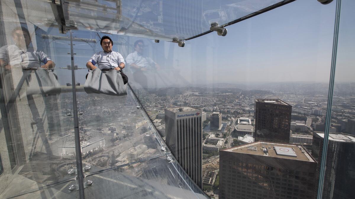 A member of the media takes a 4-second ride on the SkySlide, 1,000 feet above downtown Los Angeles at the U.S. Bank Tower. The slide is part of OUE Skyspace LA, the tallest open-air observation deck in California, offering visitors a 360-degree view of the city.