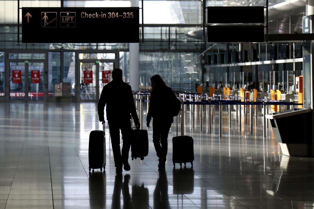 personas caminando con equipaje en la desierta sala de documentación en el aeropuerto de Múnich, Alemania,