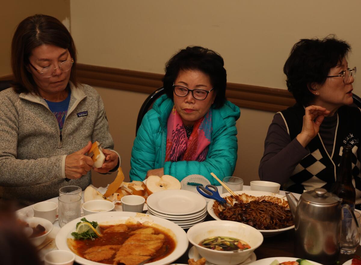Three women seated at a restaurant table laden with food