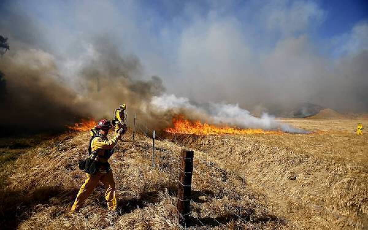 Firefighters set backfires on Federal Indian Reservation land near Banning, where a wildfire burned more than 1,500 acres and destroyed several homes on Wednesday afternoon.