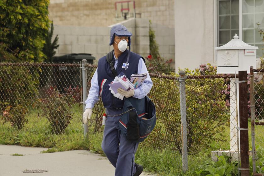 LOS ANGELES, CALIFORNIA-MARCH 14, 2020-A postal worker delivers mail in Torrance, wearing a mask and gloves. he said he had been wearing the mask for about a week. (He agreed to be photographed but didn't want his name used.) (Carolyn Cole/Los Angeles Times)
