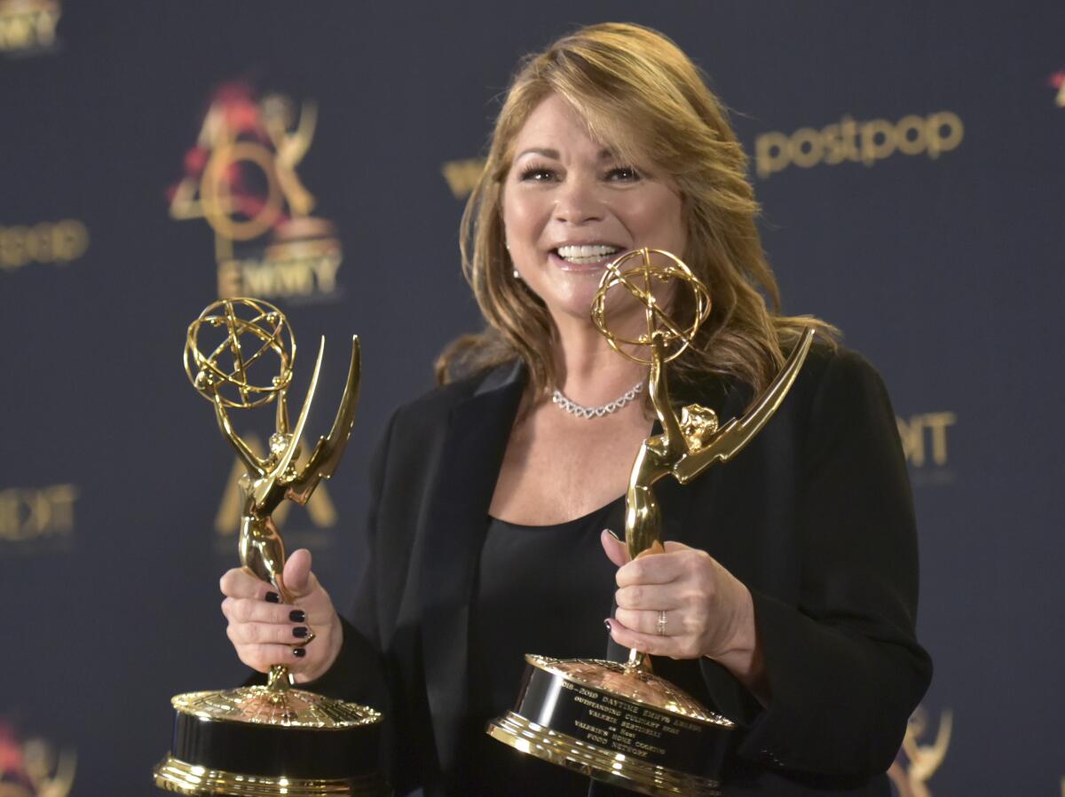 Valerie Bertinelli wears a black blouse and blazer as she holds two Daytime Emmy trophies