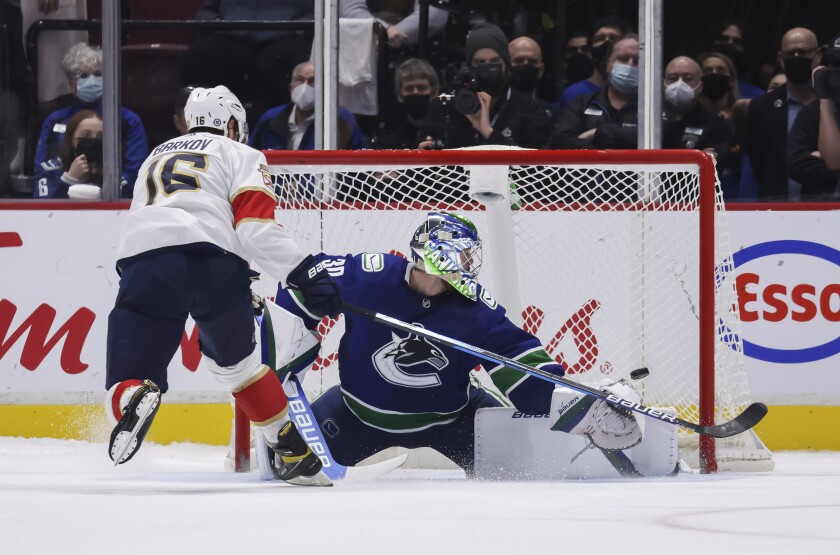Florida Panthers' Aleksander Barkov, left, scores against Vancouver Canucks goalie Spencer Martin during the shootout in an NHL hockey game Friday, Jan. 21, 2022, in Vancouver, British Columbia. (Darryl Dyck/The Canadian Press via AP)