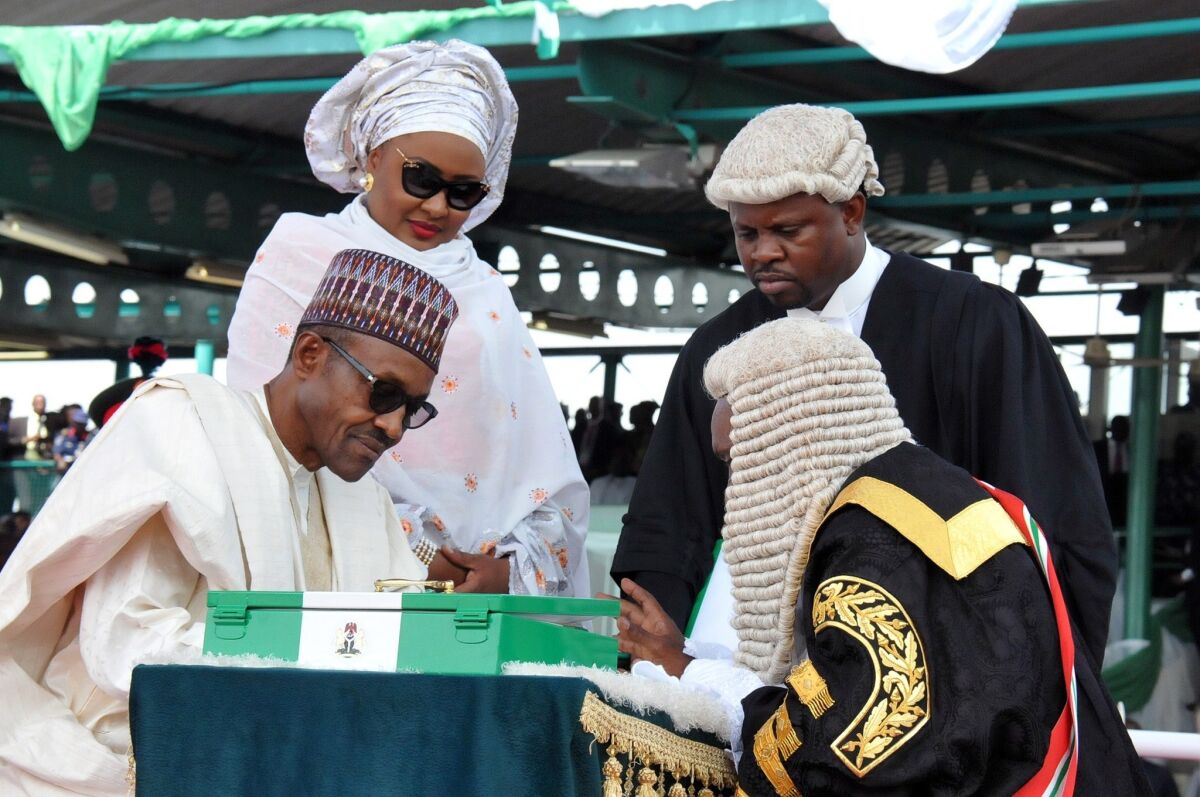 Nigerian President Mohammadu Buhari, left, sits beside his wife, Aisha, as he signs after swearing to an oath during his inauguration at Eagle Square in Abuja on Friday.