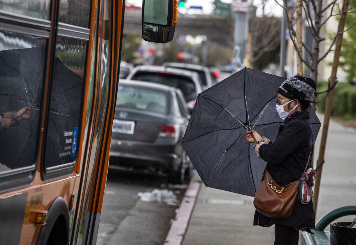  A woman waits in the rain for a bus.