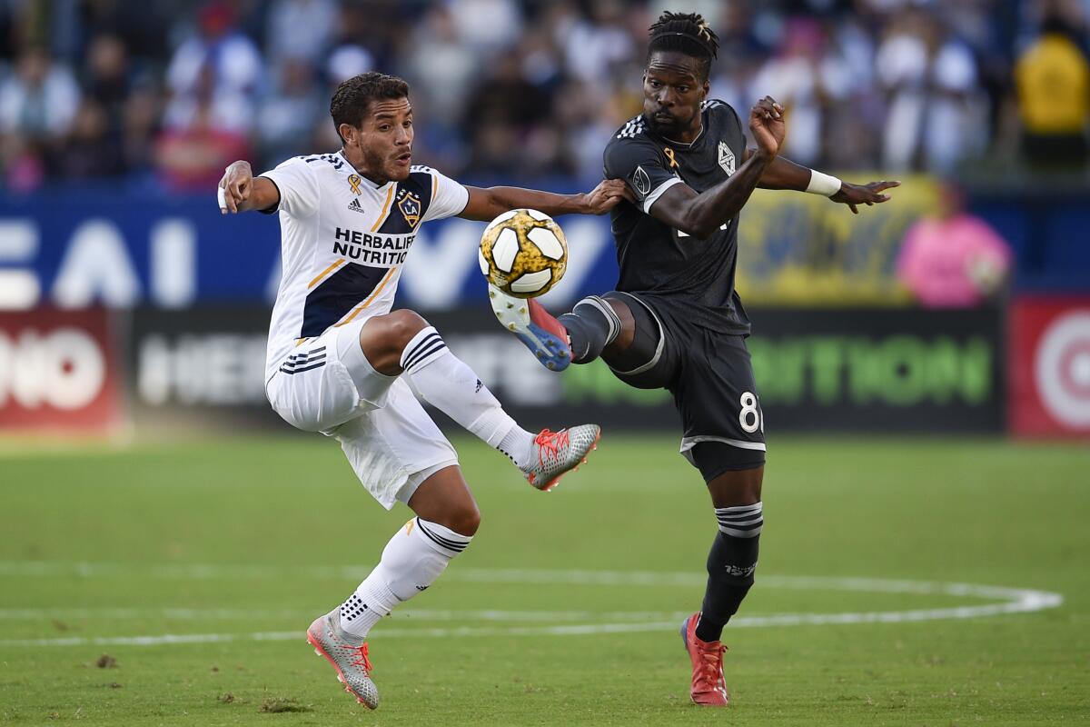 Galaxy midfielder Jonathan dos Santos, left, and Whitecaps forward Tosaint Ricketts battle for the ball 