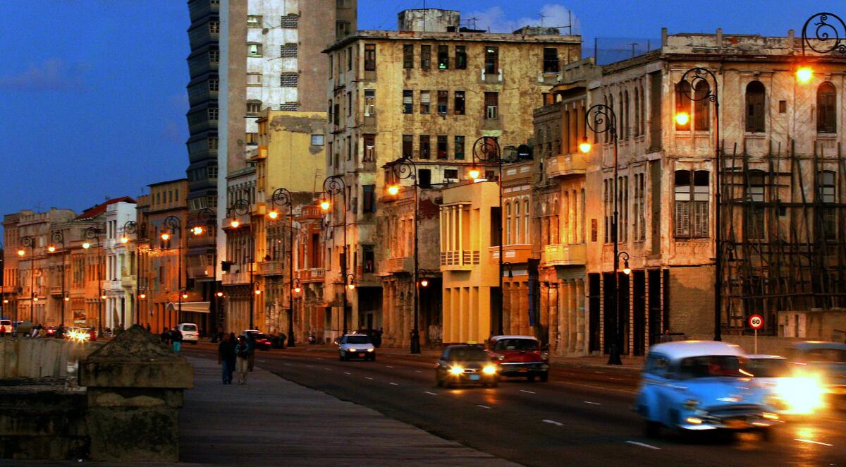 Classic American-made cars travel along the main seaside road in Havana.