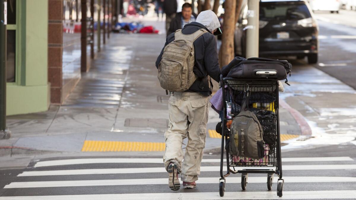 A homeless man with a grocery cart walks down a street in the Mission District on April 17 in San Francisco. The city is grappling with human waste on public streets stemming, in part, from the area's homeless population.
