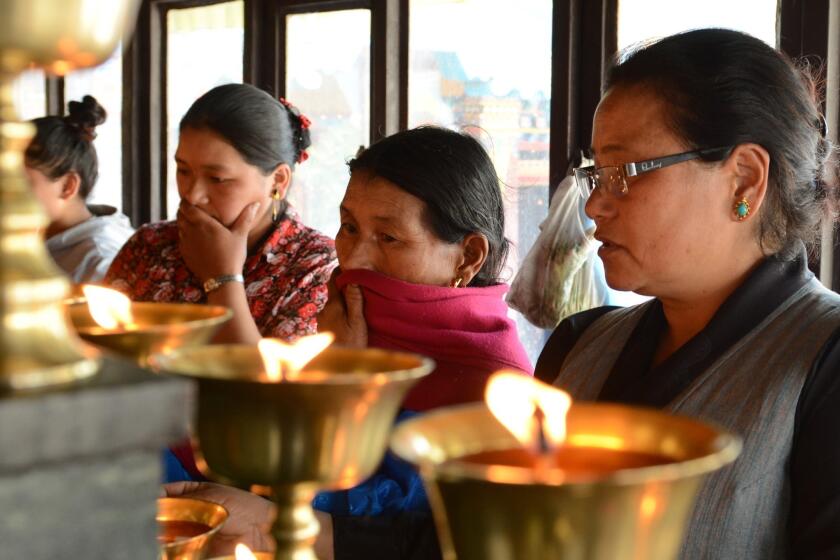 The mother of Phurtemba Sherpa (second from the right), a victim of the Everest avalanche, and family members light oil lamps Sunday as they perform rituals at the Sherpa Monastery in Katmandu.