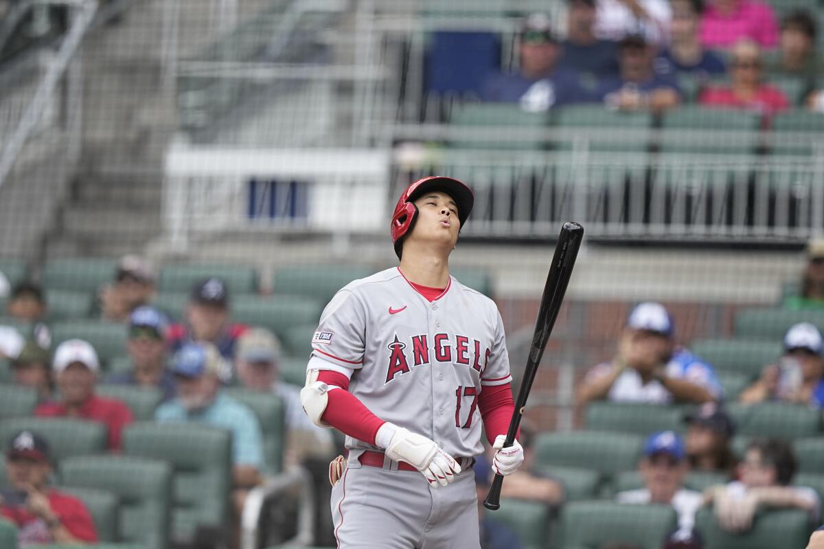 Shohei Ohtani holds the bat and looks skyward