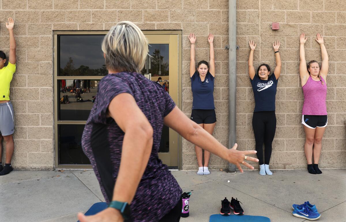 Swimmers Taylor Ault and Sabrina Benanni, from right, do stretching exercises with Olga Molotilova