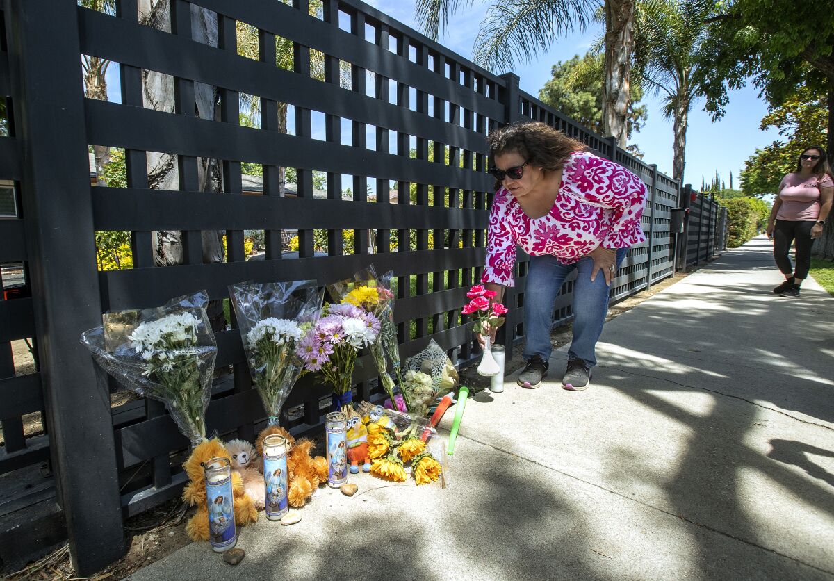 A woman places flowers at a memorial for three children.