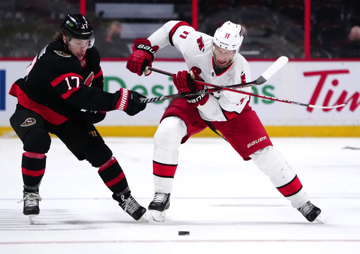 Ottawa Senators center Adam Gaudette (17) tries to keep Carolina Hurricanes center Jordan Staal (11) from the puck during the first period of an NHL hockey game Tuesday, Feb. 8, 2022, 2022 in Ottawa, Ontario. (Justin Tang/The Canadian Press via AP)