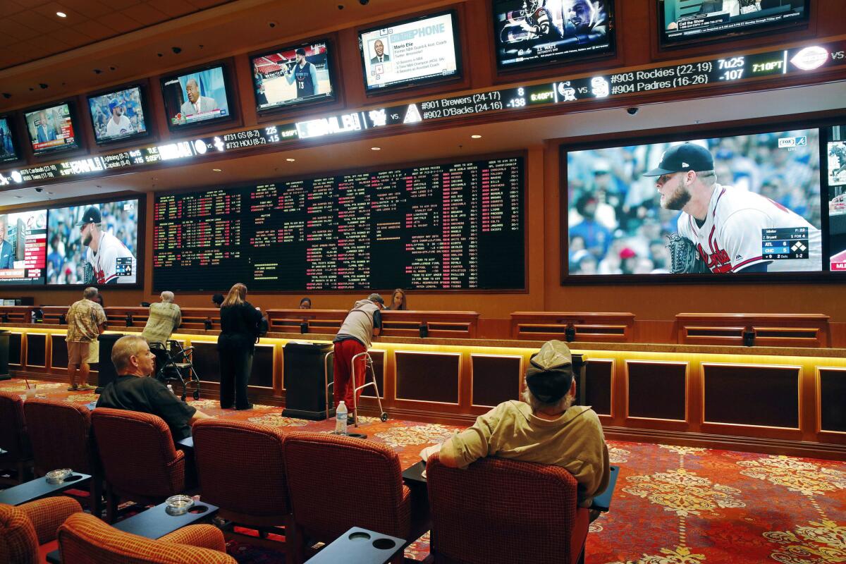People make bets in the sports book at South Point hotel and casino in Las Vegas in 2018. 
