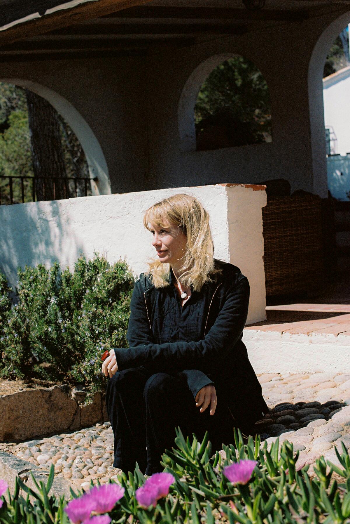 Writer Megan McDowell sits on steps in front of a patio