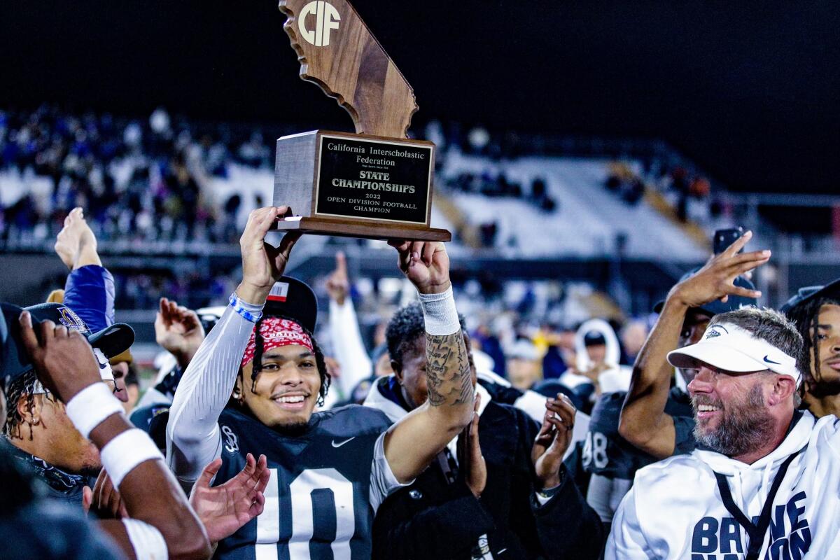 St. John Bosco quarterback Pierce Clarkson holds up the state championship trophy as coach Jason Negro celebrates.