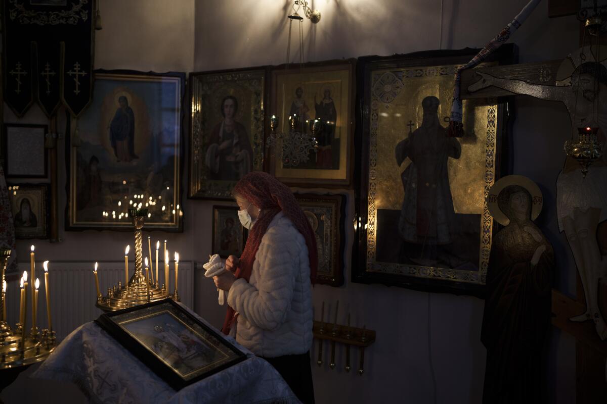 a woman in a mask stands in front of candles at a church 