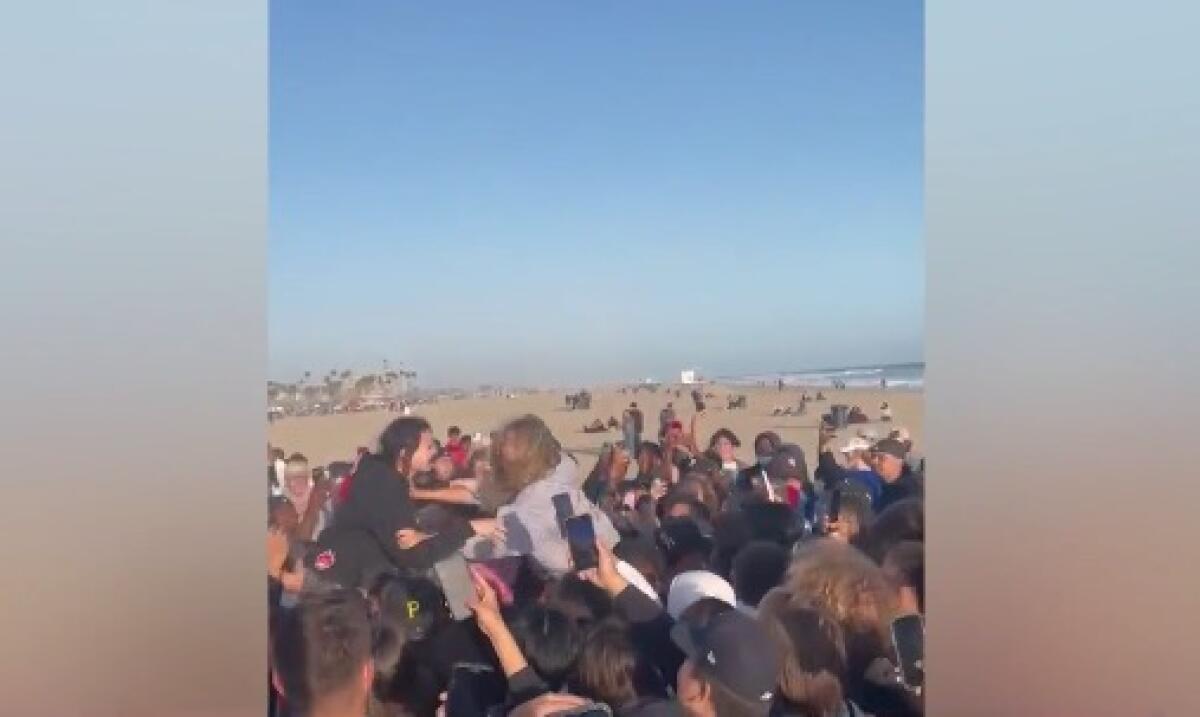 A crowd assembles in Huntington Beach on the sand near the ocean.
