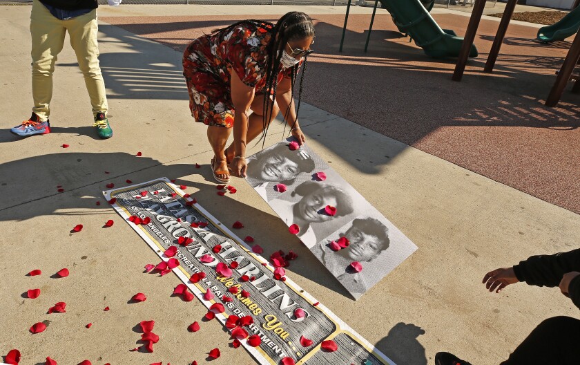 Shinese Harlins Kilgore, cousin of Latasha Harlins, places rose petals on photos of Latasha