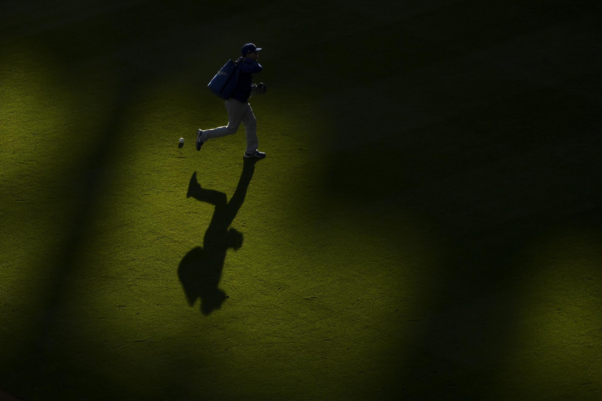 A shadow is cast as Los Angeles Dodgers personnel runs a bag across the outfield before Game 2.