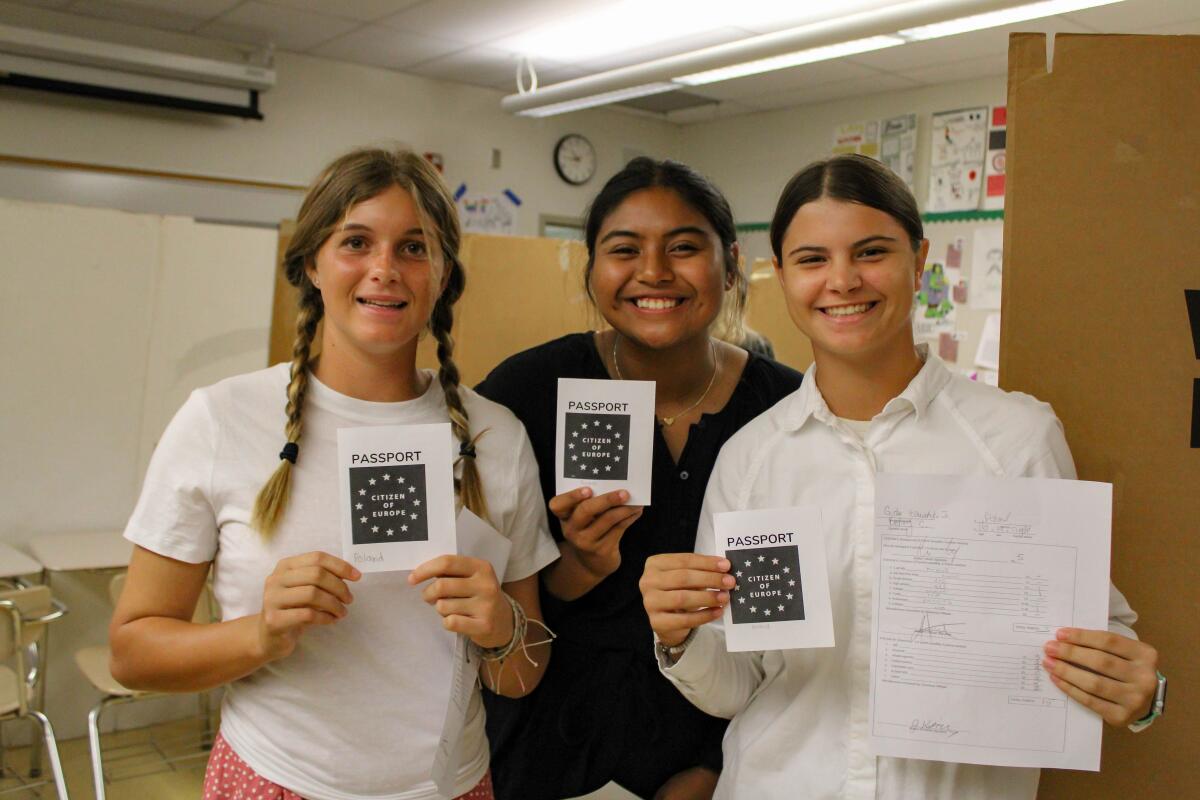Edison High juniors show off passports they received after participating in an Ellis Island Experience simulation.
