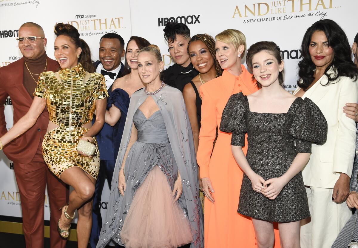 A group of dressed-up people poses on a red carpet.