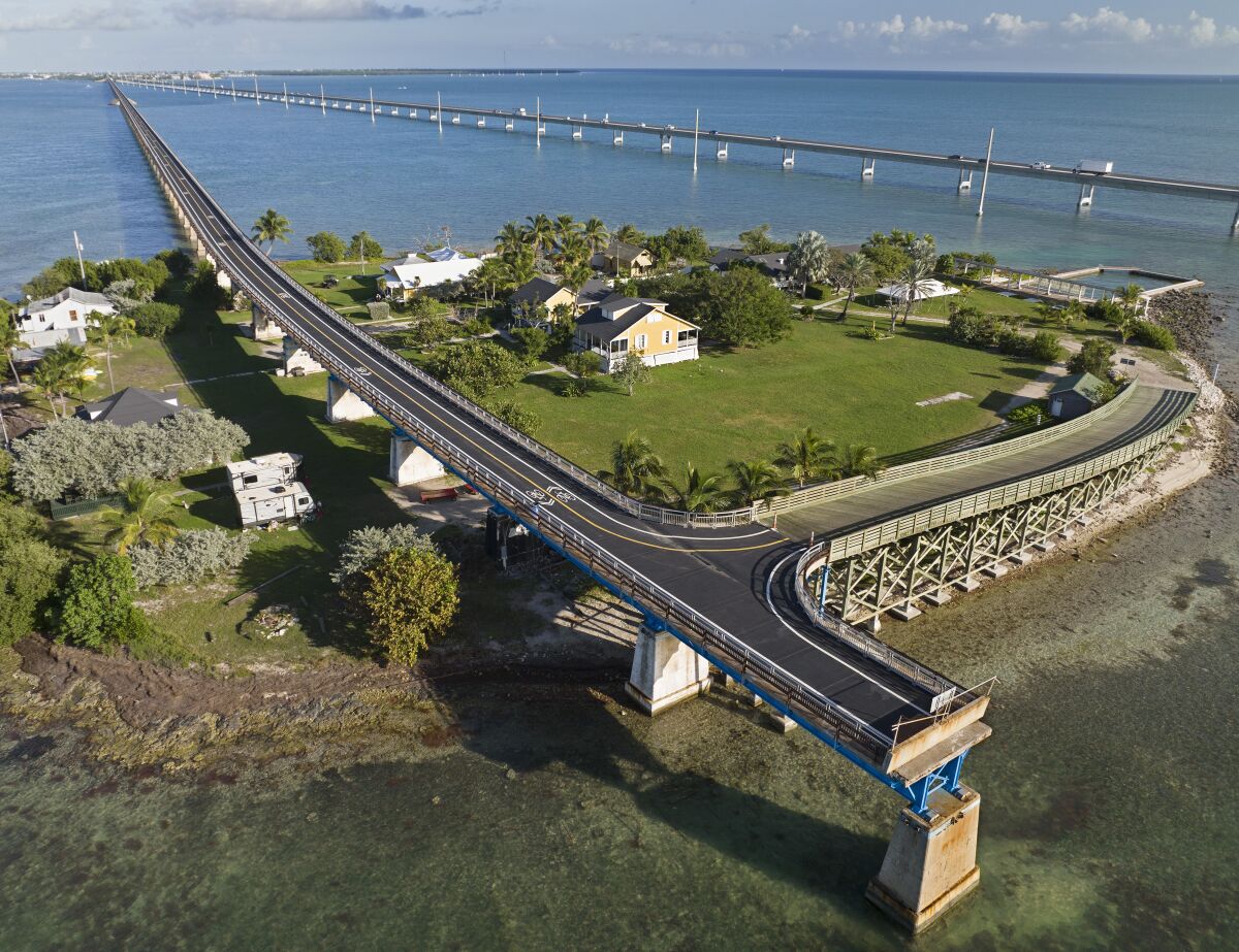 This Monday, Jan. 10, 2022, drone aerial photo provided by the Florida Keys News Bureau shows the Old Seven Mile Bridge ready for its Wednesday, Jan. 12, 2022, reopening to pedestrians, bicyclists, anglers and visitors to Pigeon Key (island shown in photo). The old bridge originally was part of Henry Flagler's Florida Keys Over-Sea Railroad that was completed in 1912. The railroad ceased operations in 1935 and was converted into a highway that opened in 1938. In 1982, construction was completed on a new Seven Mile Bridge, behind, that continues to carry motor vehicles between the South Florida mainland throughout the Keys to Key West. (Andy Newman/Florida Keys News Bureau via AP)