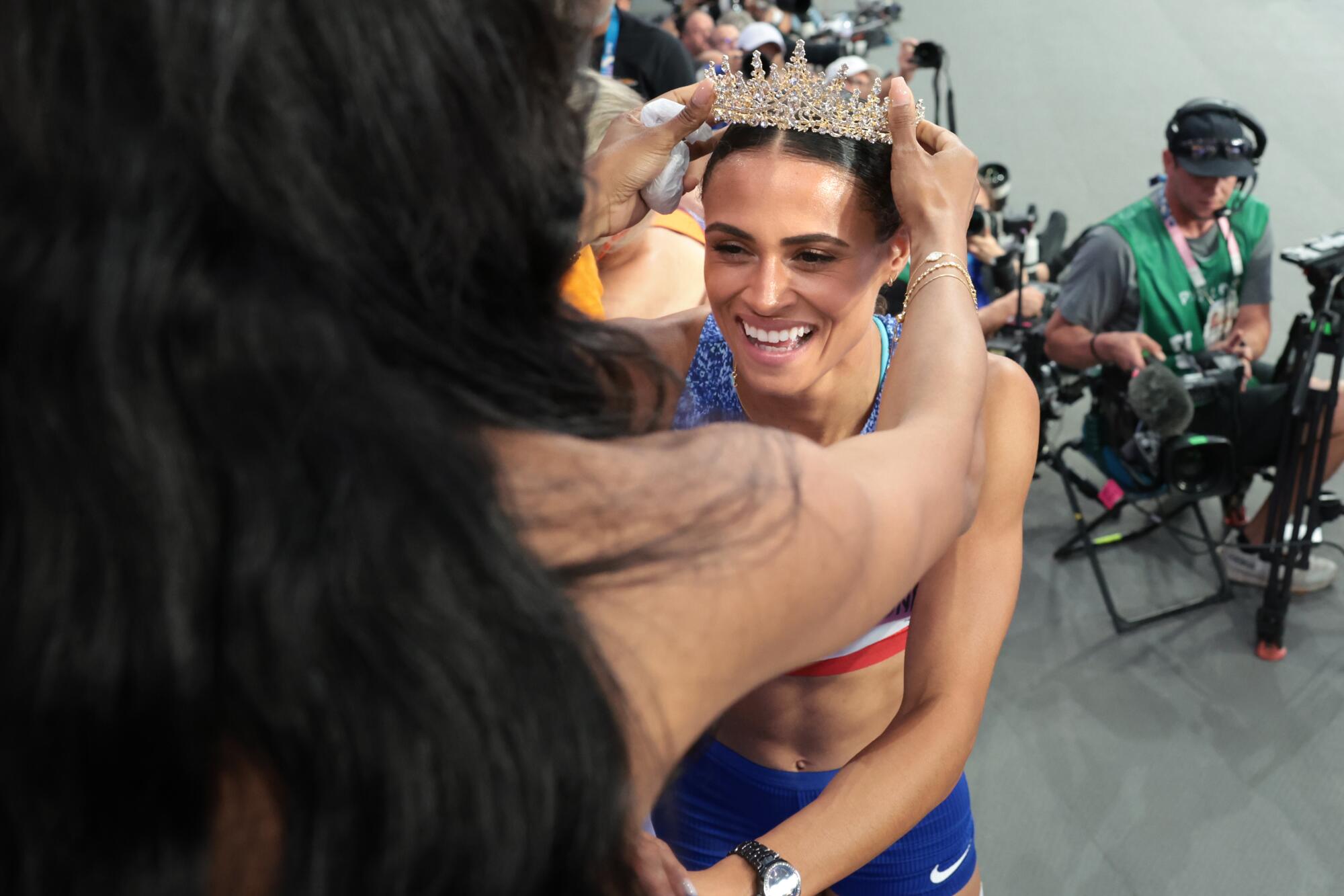 Sydney McLaughlin-Levrone receives a crown from her sister after winning the women's 400 hurdles.