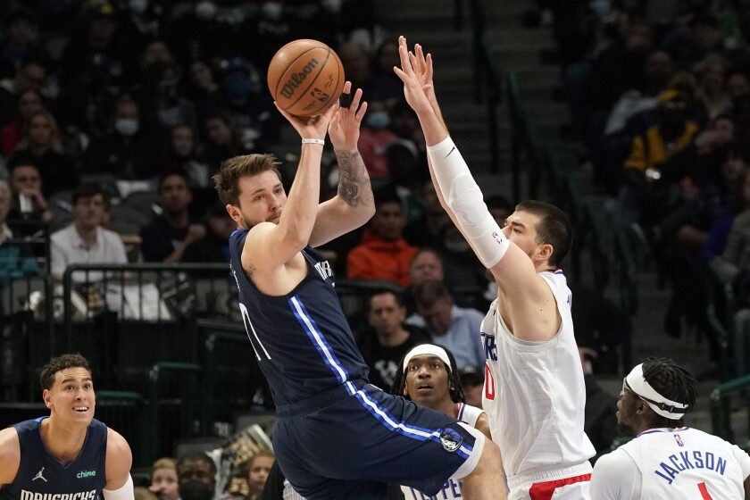 The Mavericks' Luka Doncic passes as he's defended by the Clippers' Ivica Zubac (40), Terance Mann and Reggie Jackson (1).
