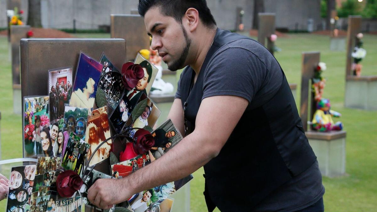 Brian Martinez, 31, attaches a wreath made of family photos to the chair erected to honor his father, the Rev. Gilbert X. Martinez. in the Field of Chairs at the Oklahoma City Memorial on Wednesday.