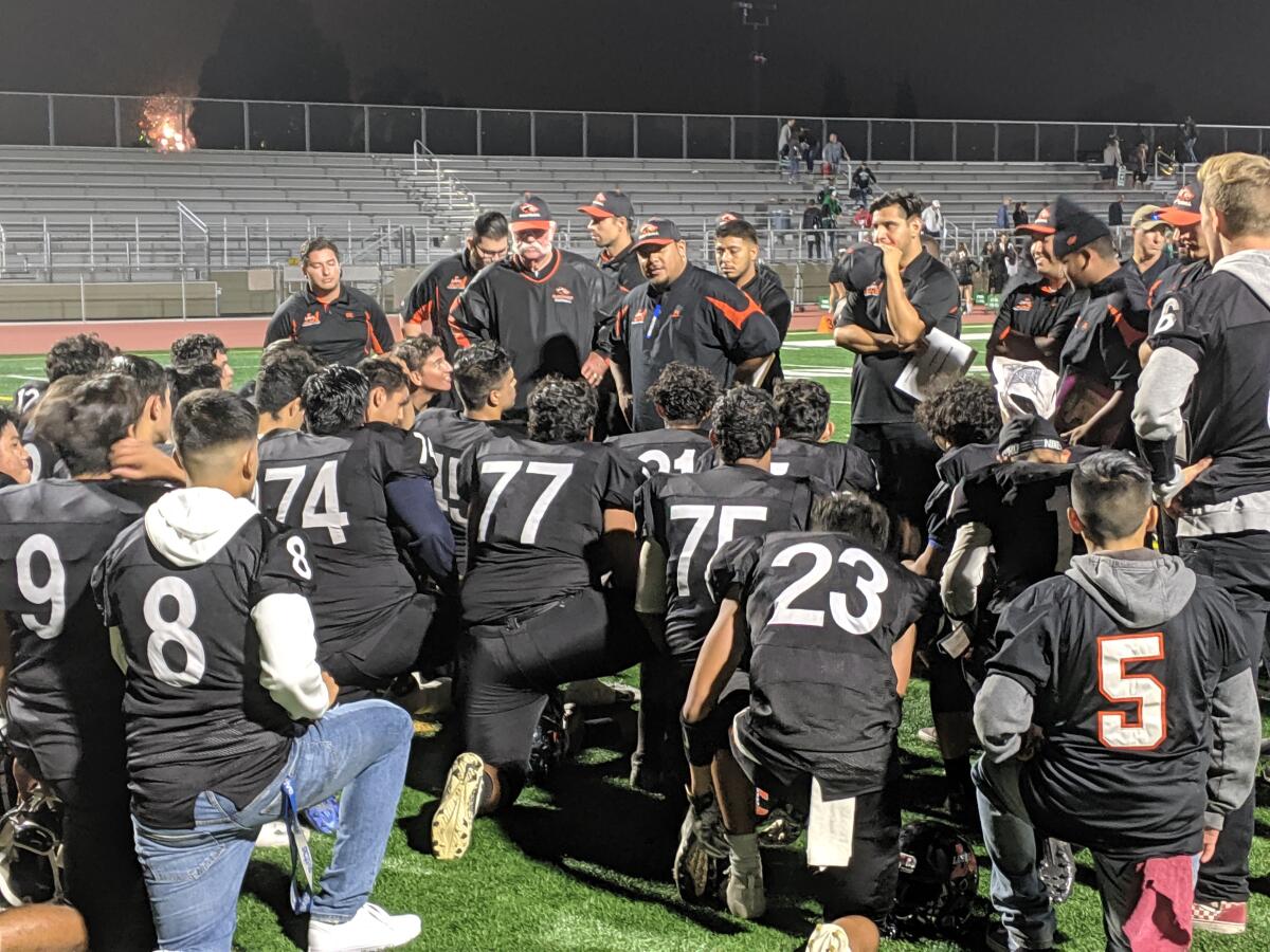 Los Amigos coach Maopu Tuato addresses his team after its 27-21 nonleague victory against Costa Mesa on Friday at Garden Grove High.