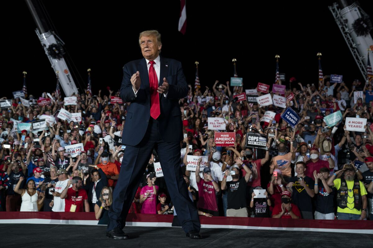 President Trump walks off clapping as a crowd cheers at a campaign rally at Orlando Sanford International Airport on Monday.