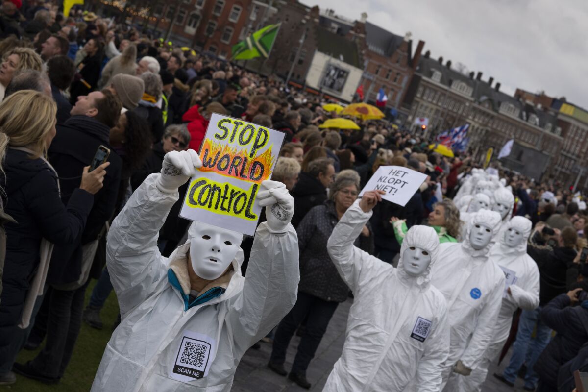 Protesters gather in Amsterdam to protest, including people in white outfits and masks