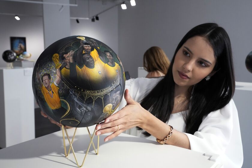 La artista paraguaya Lili Cantero observa uno de los balones que pintó, con la imagen del as brasileño Pelé, en una exposición en Katara Cultural Ville, en Doha, Qatar, el 24 de noviembre de 2022. (AP Foto/Jorge Sáenz)