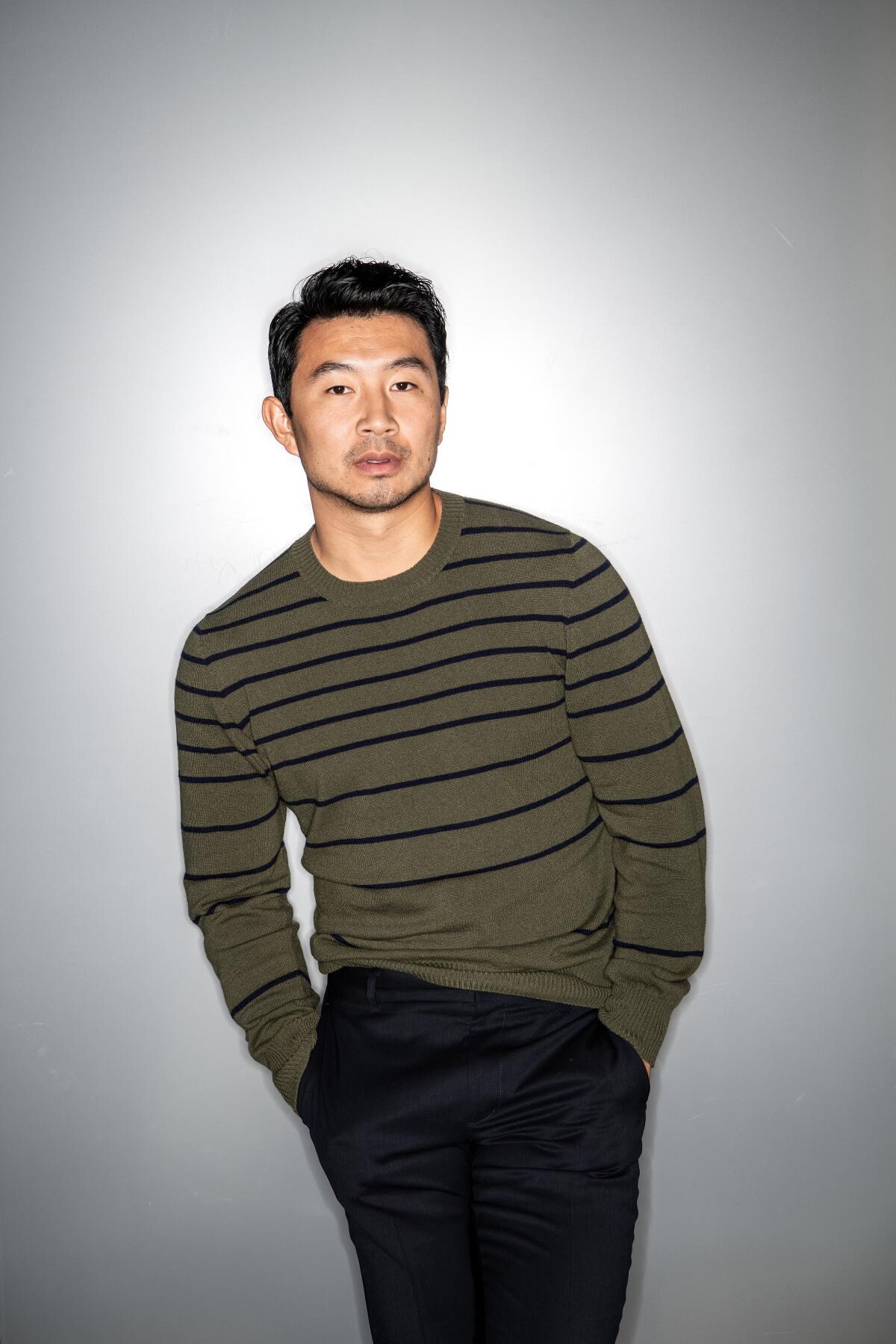 Portrait of actor Simu Liu in a green and black striped sweater