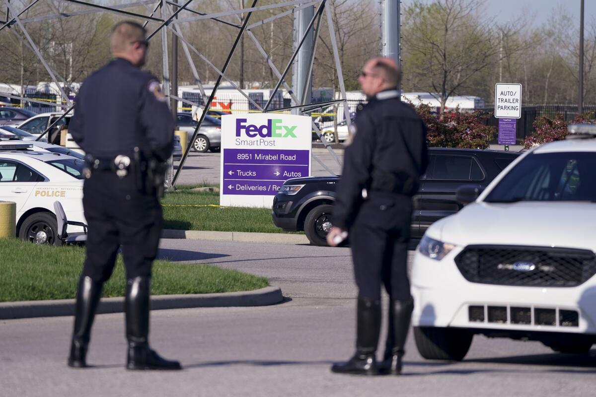 Police stand near the scene where multiple people were shot at a FedEx facility in Indianapolis on April 16.