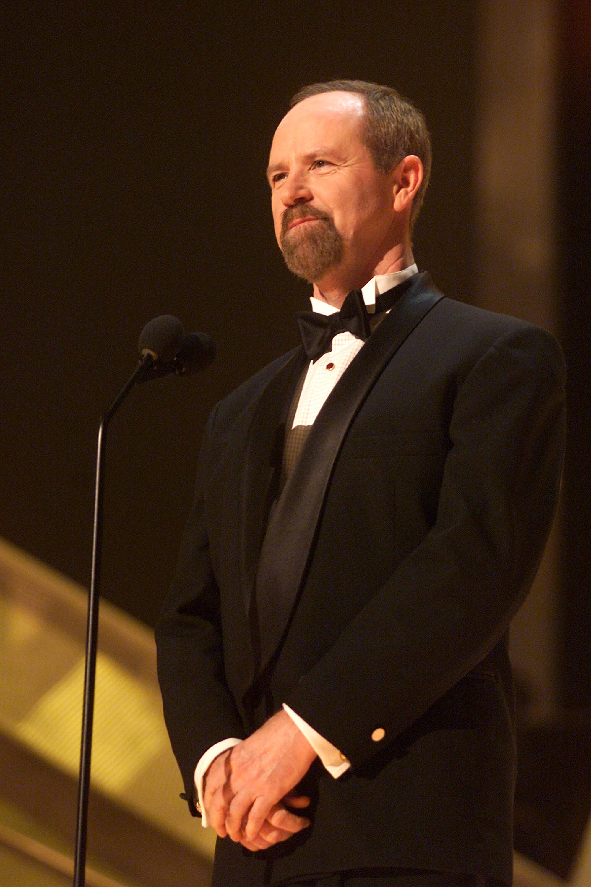 A smiling goateed man in a tuxedo